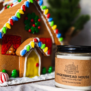 
                  
                    Load image into Gallery viewer, Soy candle with brown label that reads gingerbread house and ginger, vanilla icing, and sugar. A colorful gingerbread house in the background.
                  
                